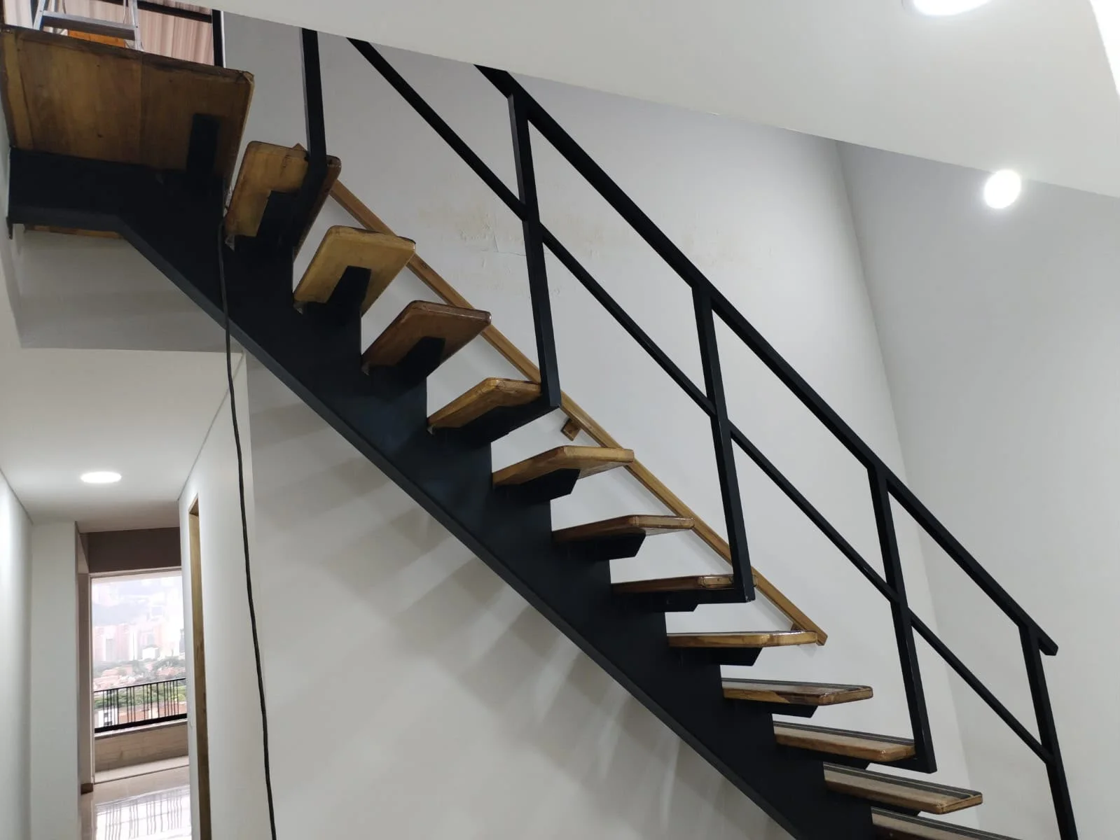 Escalera con estructura metálica, peldaños de madera y baranda